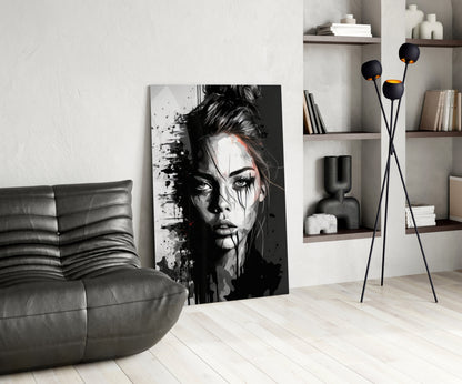 Black and white portrait glass art leaning against wall in modern living room with grey sofa and shelving.