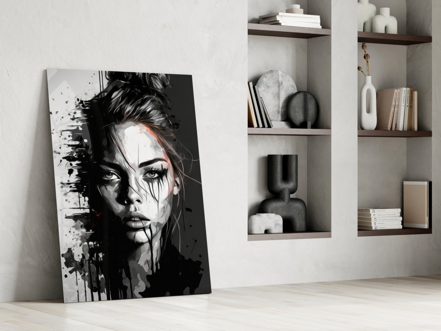Black and white abstract portrait canvas leaning against white wall beside built-in shelving with decorative objects.