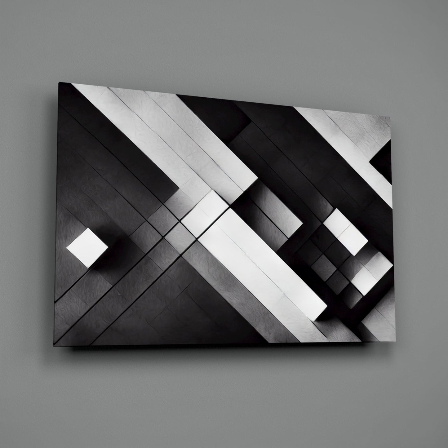 Black and white geometric glass wall art with diagonal intersecting planes and metallic brushed surface finish, displayed at an angle against gray background.