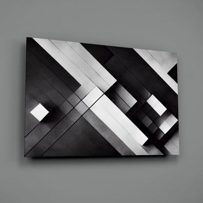 Black and white geometric glass wall art with diagonal intersecting planes and metallic brushed surface finish, displayed at an angle against gray background.