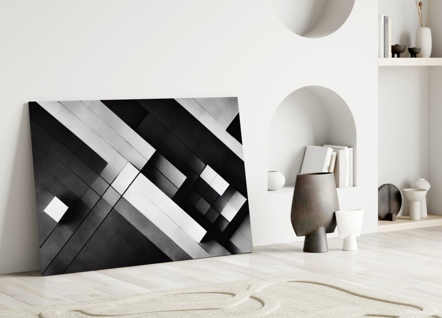 Modern minimalist interior display featuring black and white geometric glass wall art leaning against white wall with neutral décor accessories.