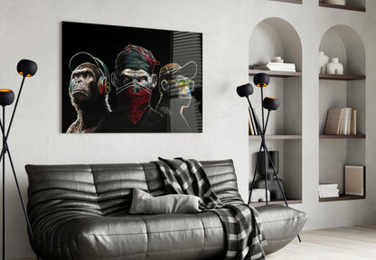 Neon Lines Glass Wall Art depicting three stylized monkeys with headphones, face mask, and sunglasses on black background, displayed above gray leather sofa in modern living room.