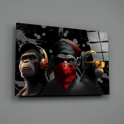Three stylized monkeys wearing colored headphones and a red bandana against a black and gray splattered background on glass wall art.