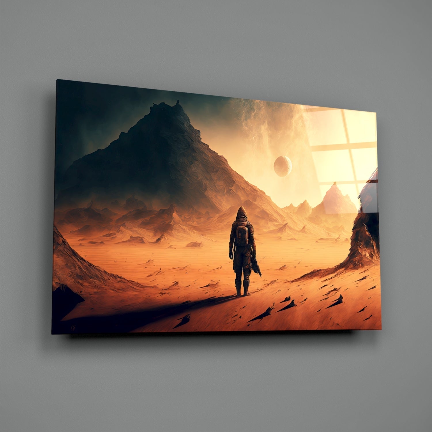 Framed glass wall art depicting a solitary figure in space suit standing on russet desert landscape beneath towering mountain and golden sky with planetary body.