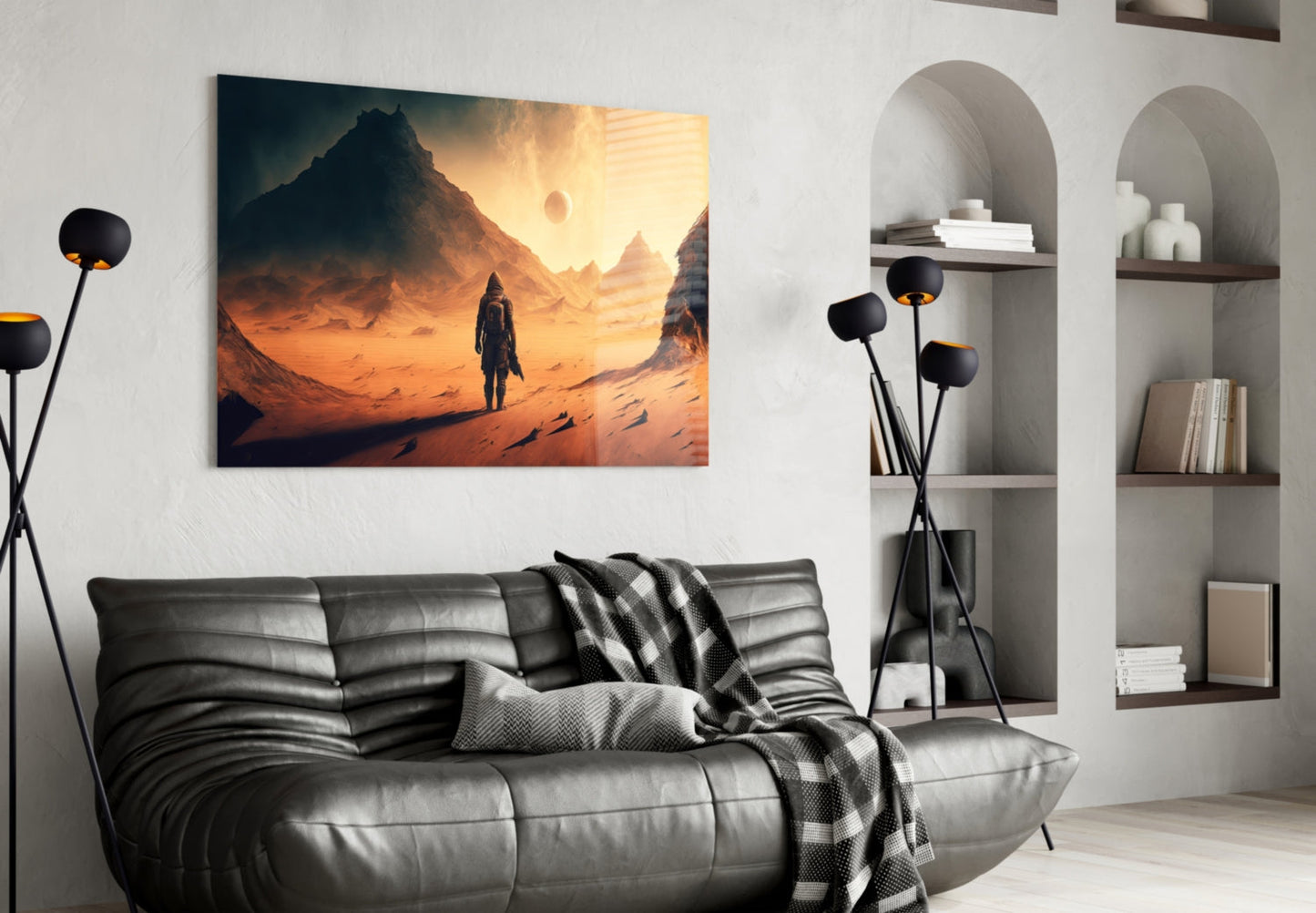 Glass wall art depicting a figure standing in an orange desert landscape with mountains, displayed above a gray leather sofa in a modern living room.
