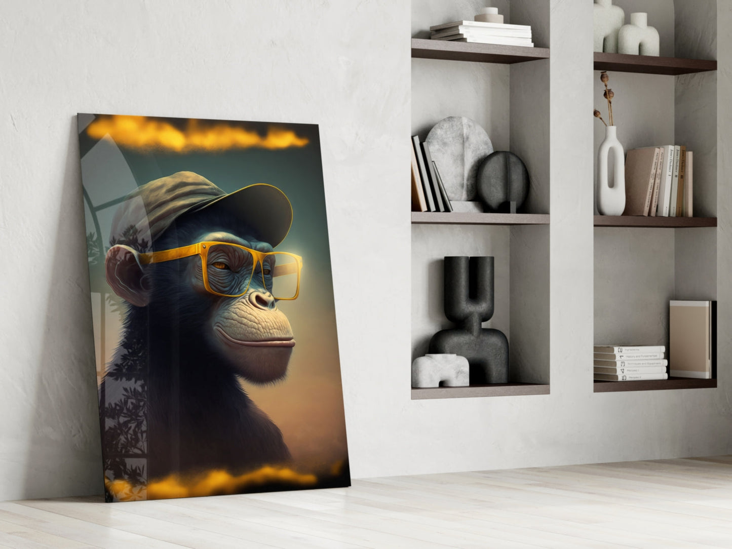 Wise Monkey glass wall art leaning against white wall beside built-in shelving, showing chimp wearing yellow sunglasses and cap against warm golden background.