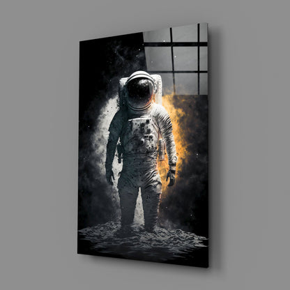 Angled view of glass wall art displaying a white-suited astronaut standing on lunar surface with dramatic gold and white light effects against black background.
