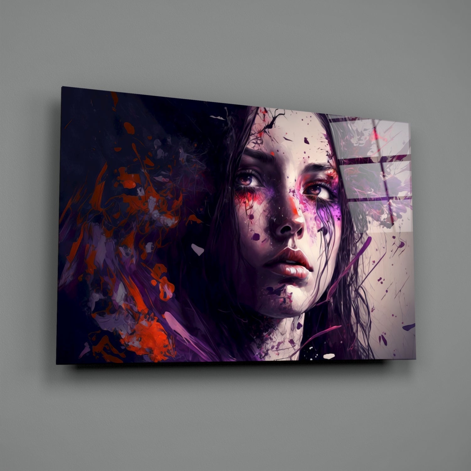 Glass wall art panel displaying a woman's face in purple and orange tones with abstract splatter effects, mounted on gray wall.