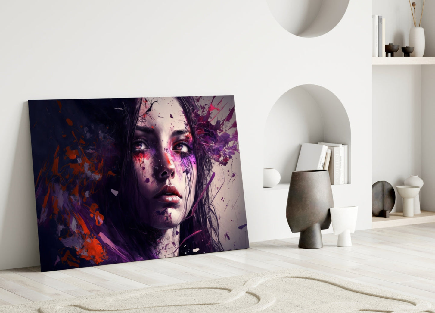 Colorful glass art panel leaning against white wall displays abstract portrait with purple, red, and orange paint splatters in minimalist interior.
