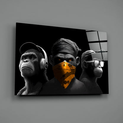 Three stylized monkeys in black and white with gold accents displayed on chrome glass wall art against gray background.