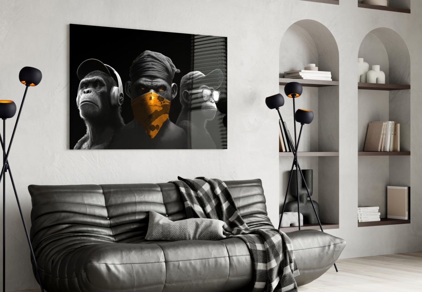 Black and white three wise monkeys glass wall art with gold accents displayed above gray leather sofa in modern living room.