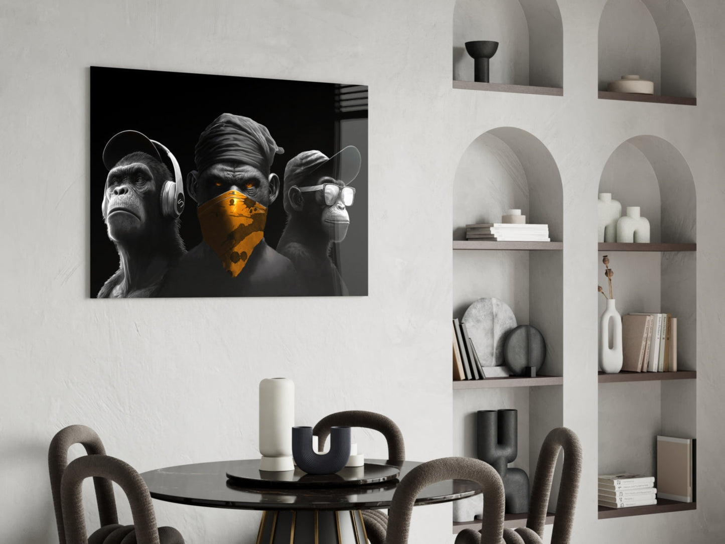 Chrome three wise monkeys glass wall art mounted above black dining table in modern white interior with built-in shelving.