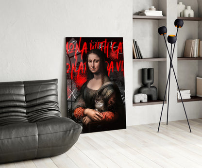 Modern living room displaying glass wall art of Mona Lisa with red graffiti text and holding a cat, leaned against white wall beside gray leather chair.