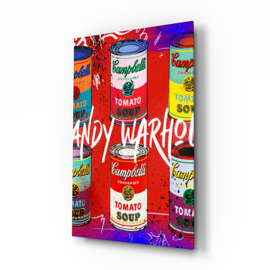 Angled 3/4 view of glass wall art featuring colorful pop art Campbell's soup cans with "ANDY WARHOL" text on vibrant red, blue, and purple background.