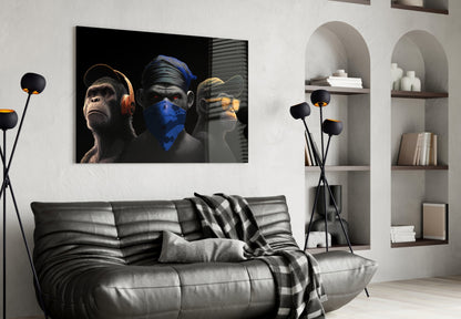 Three stylized monkeys wearing headphones, blindfold, and earpiece displayed above black leather sofa in modern living room setting.
