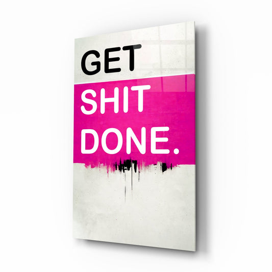 Angled view of a glass wall art panel with "GET SHIT DONE." text on hot pink and cream sections with black drip effect.