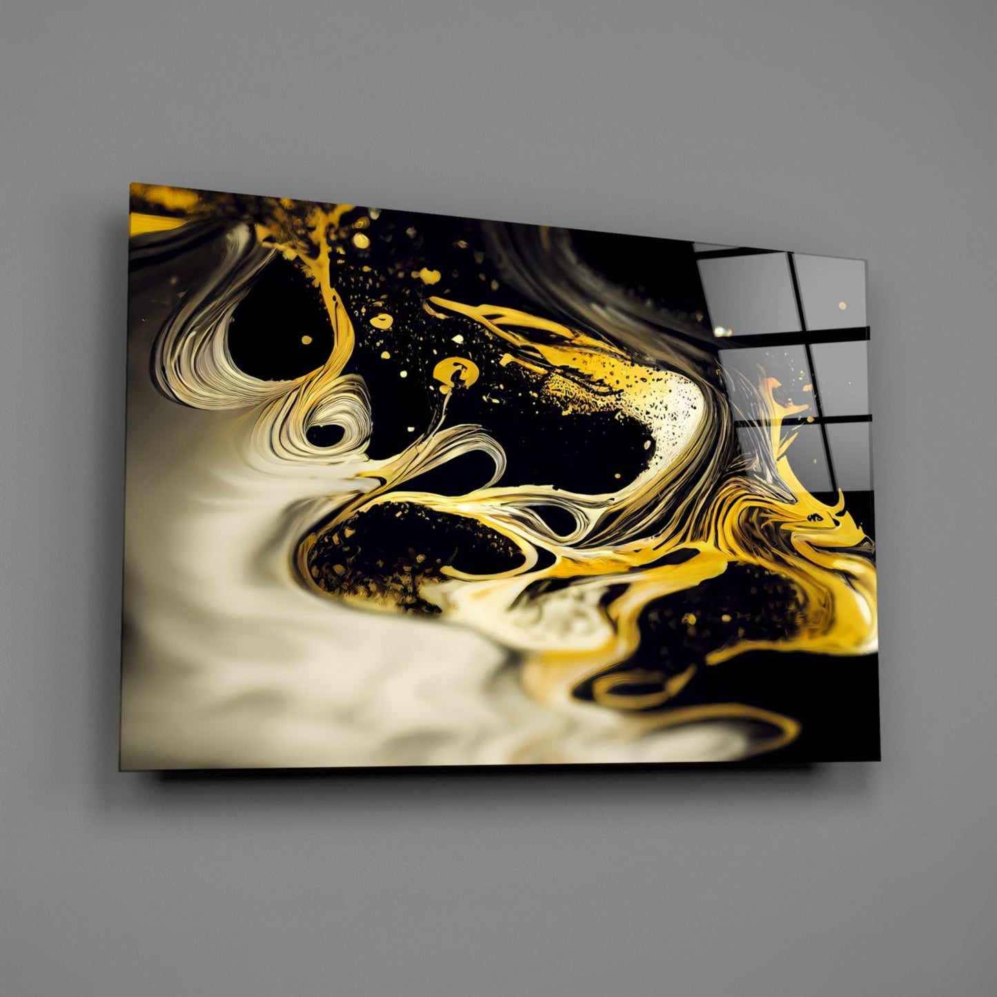 Gold and cream liquid swirls with black splashes on glass wall art mounted at an angle against gray wall.
