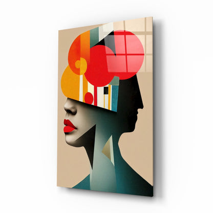 Glass wall art displaying a stylized profile head filled with geometric shapes in red, orange, yellow, teal, and black on beige background, shown at three-quarter angle.