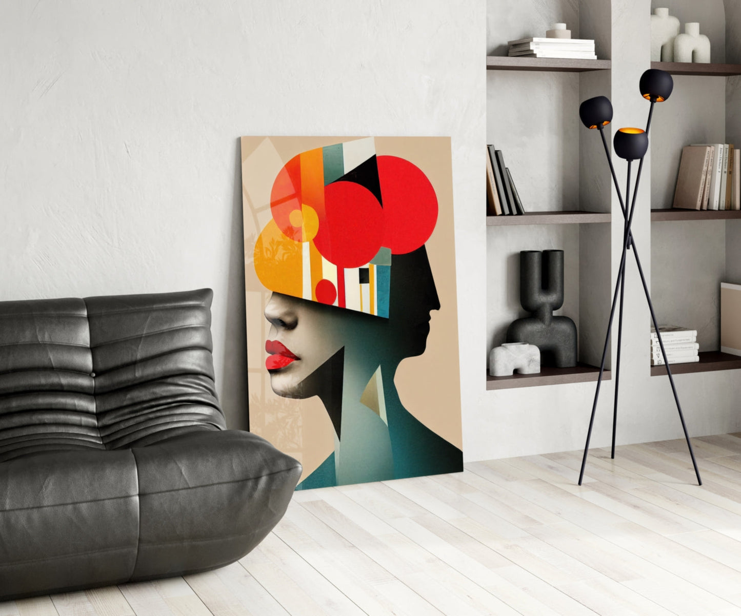 Modern living room interior featuring geometric abstract portrait artwork leaning against wall beside black leather chair and floor lamp.