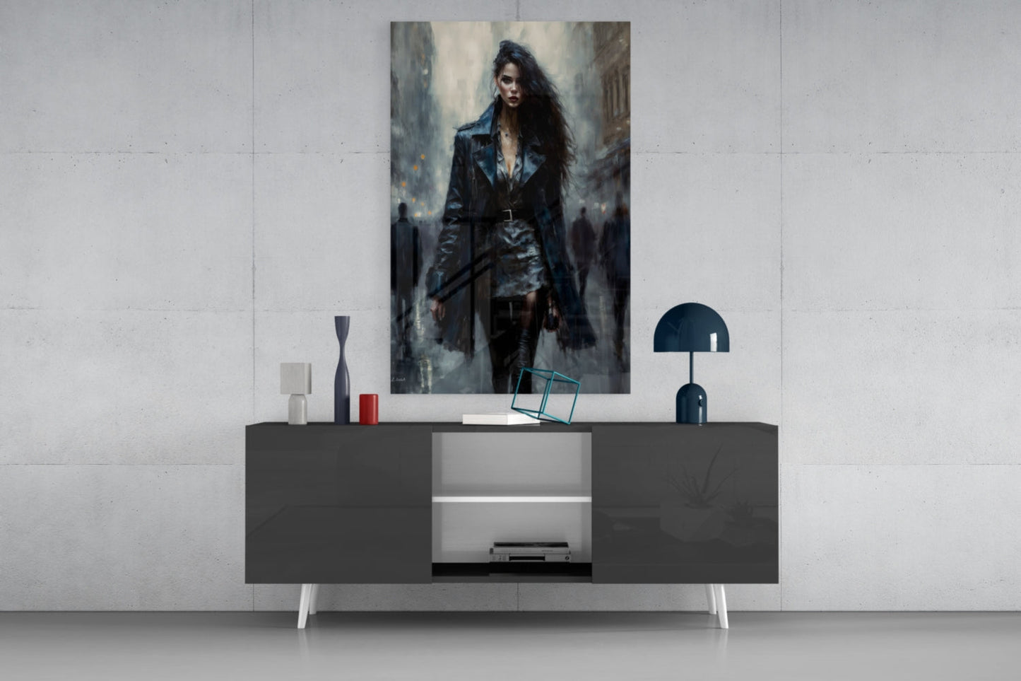 Contemporary living room display showing glass wall art of a woman in dark clothing centered above a dark console table with white legs and decorative accessories.