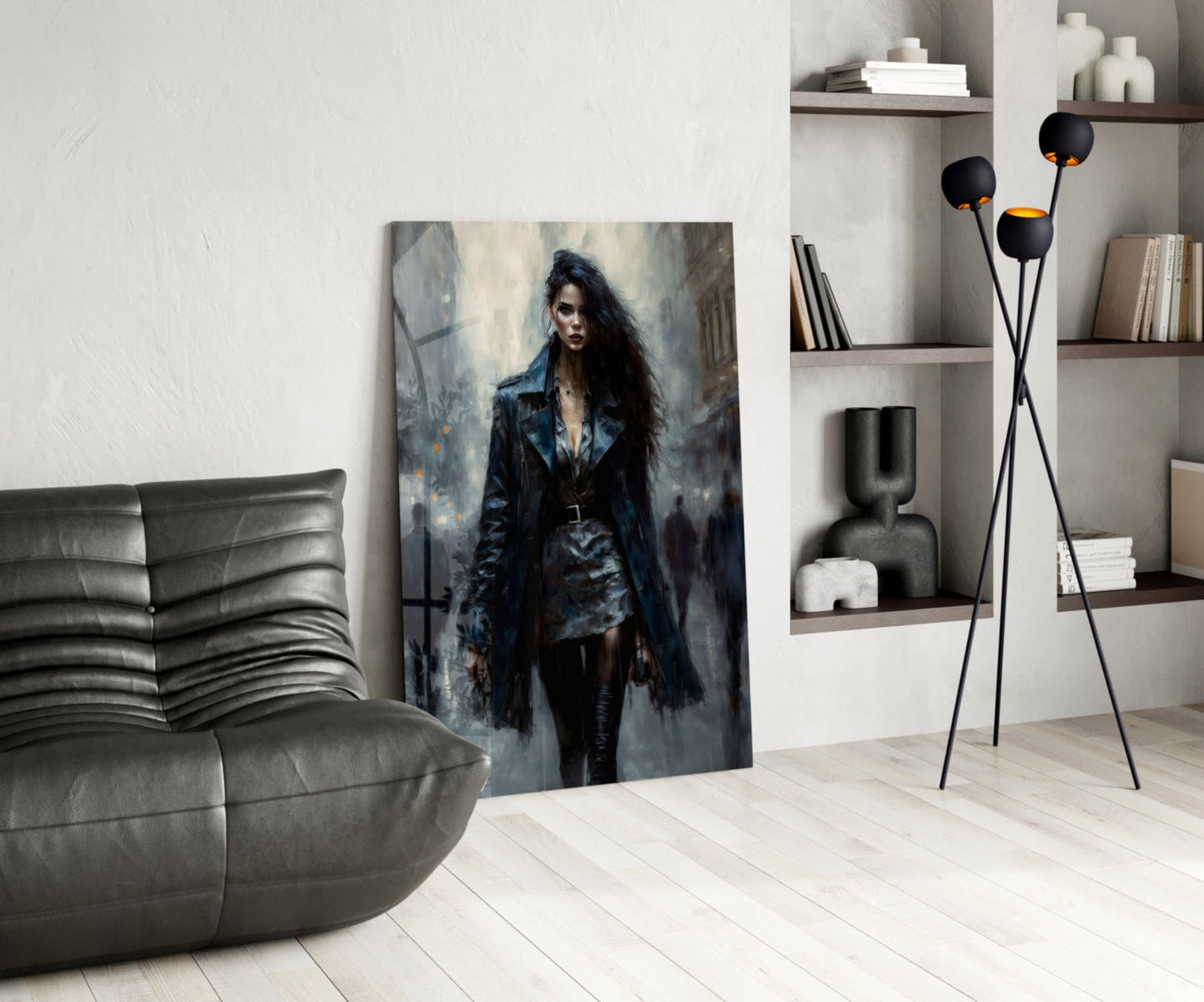 Modern living room interior featuring glass wall art of a dark-haired woman in black coat displayed leaning against white wall near gray sofa.