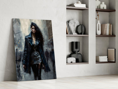 Glass wall art depicting a woman in dark leather jacket and black clothing against moody grey urban background, leaning against white wall beside wooden shelves.
