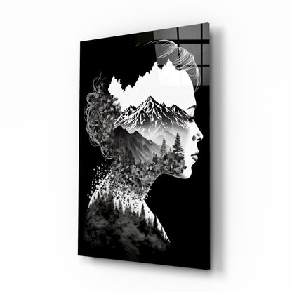 Black and white double exposure glass wall art showing a woman's profile with mountains and forest layered within her silhouette against dark background.