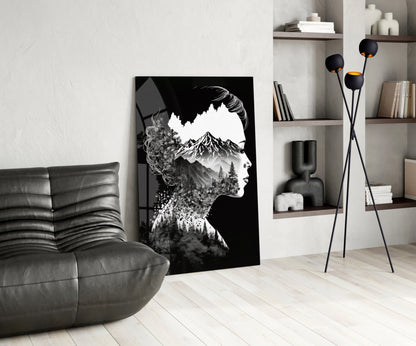 Black and white double exposure glass art featuring a woman's profile merged with mountain and forest imagery, displayed in a modern living room setting.