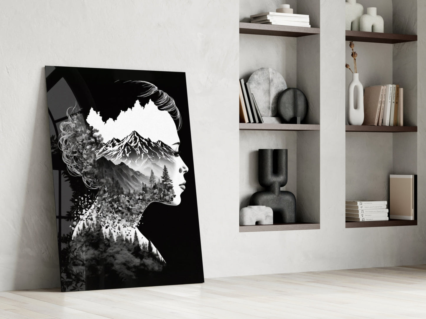 Black and white double-exposure glass art leaning against white wall, depicting woman's profile with mountain and forest landscape overlay, displayed beside wall-mounted shelving unit.