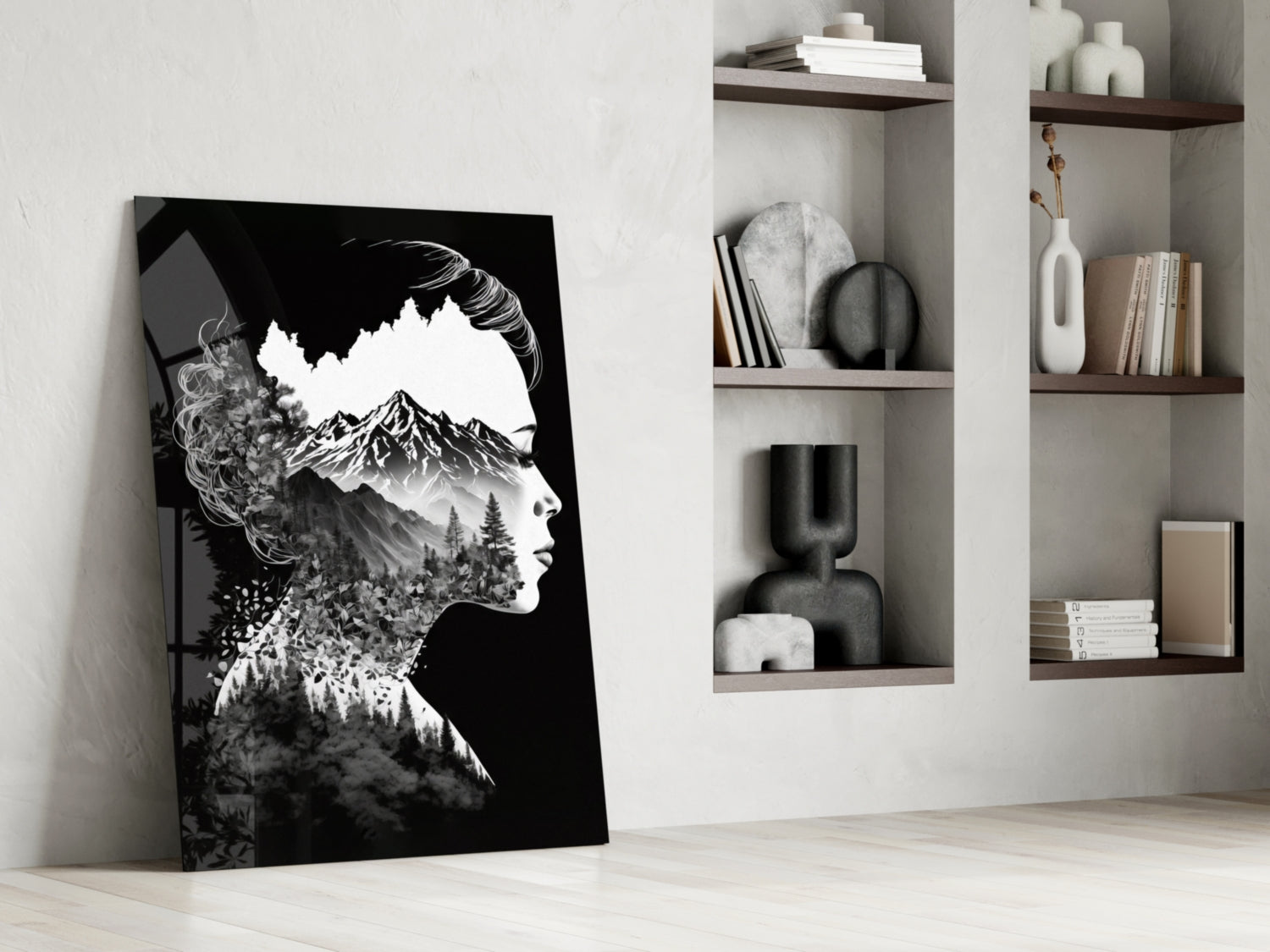 Black and white double-exposure glass art leaning against white wall, depicting woman's profile with mountain and forest landscape overlay, displayed beside wall-mounted shelving unit.