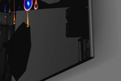 Neon glowing hanging glass art pieces with blue and orange accents displayed in dark interior space.