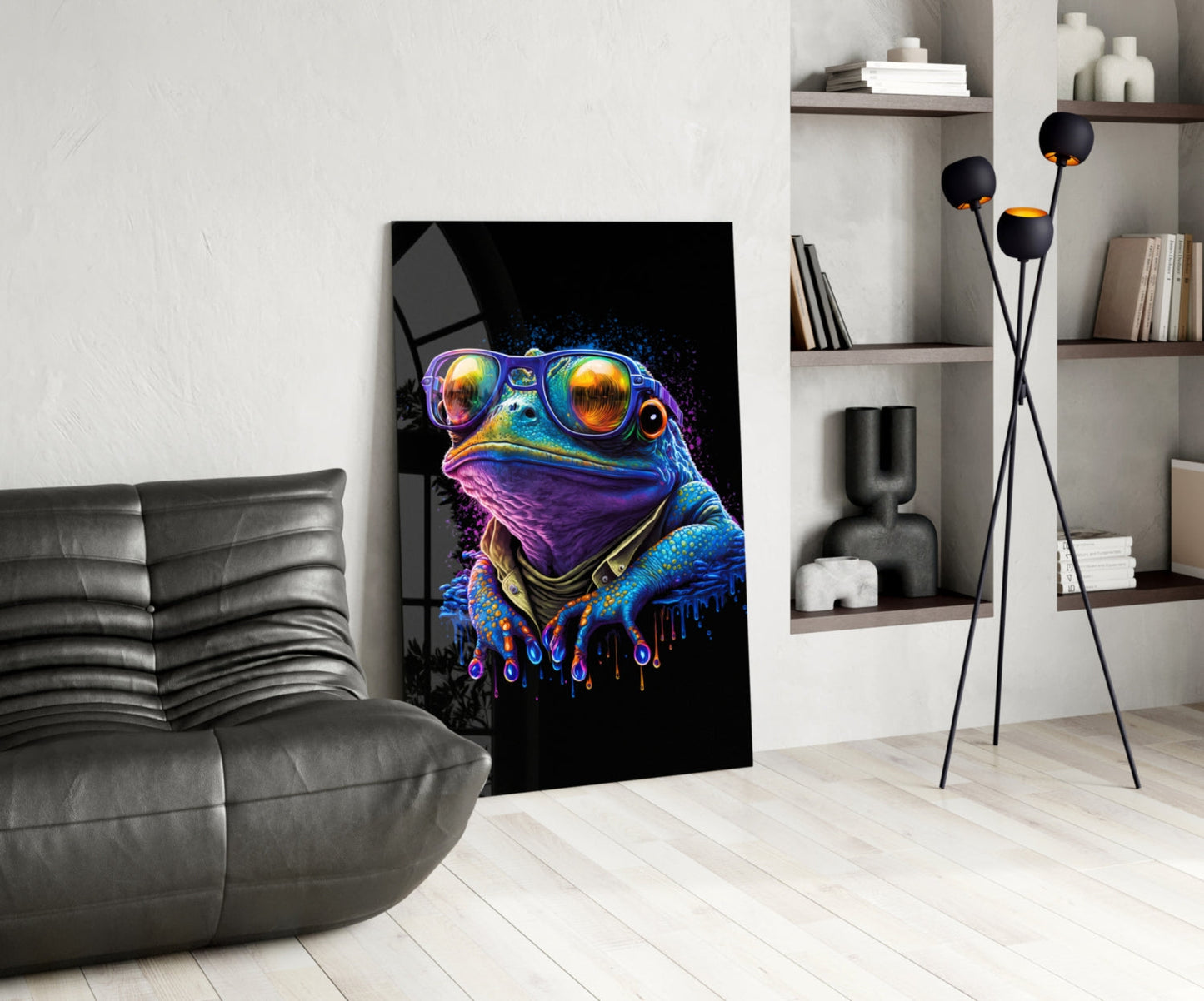 Vibrant neon frog wearing sunglasses displayed as glass wall art in modern living room setting with gray sofa and shelving.
