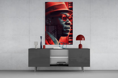 Vertical glass wall art featuring a stylized portrait of a man wearing red sunglasses and hat, displayed above a modern gray console table with decorative accessories.