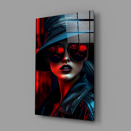 Glass wall art mounted on gray wall showing stylized woman wearing red-tinted sunglasses and blue-black jacket with red and blue lighting effects.