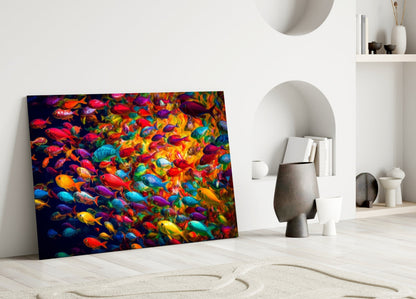 Colorful glass wall art panel leaning against white wall displays vibrant school of multicolored tropical fish on dark background.