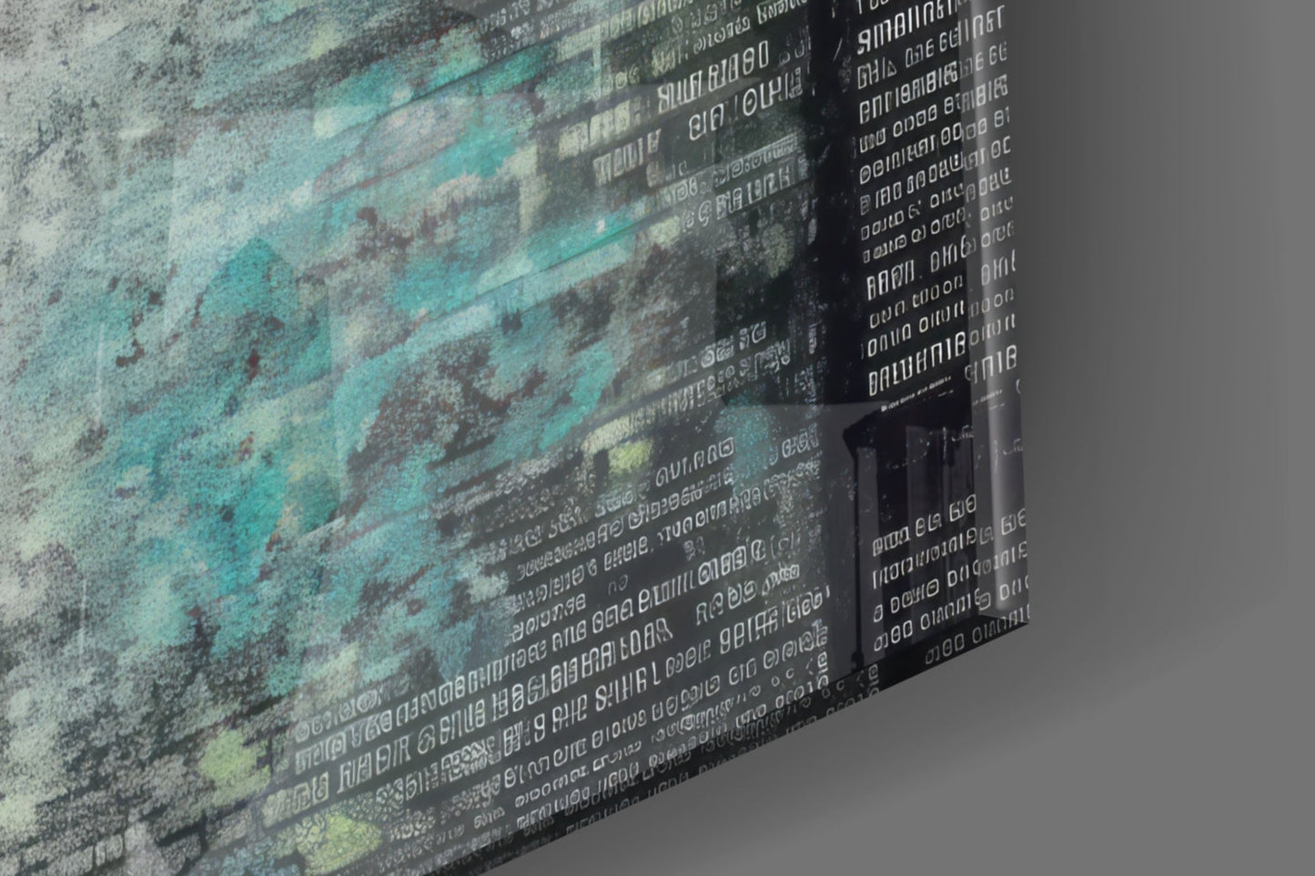 Close-up angled view of glass wall art showing layered turquoise and gray textures with overlaid white text, photographed from the side to display depth and transparency.