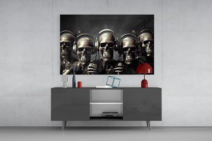 Five metallic skulls wearing headphones displayed on a dark TV console against a white wall.