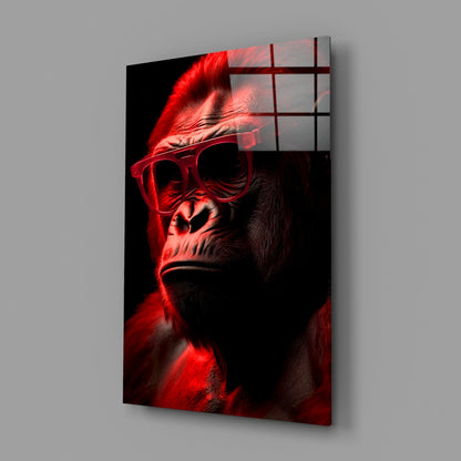 Angled view of glass wall art depicting a stylized ape wearing red sunglasses against black background with grid overlay.