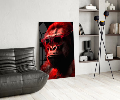 Red-lit primate wearing sunglasses displayed as glass art in modern living room with gray sofa and shelving.