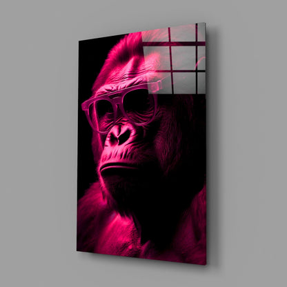 Angled view of neon pink illuminated gorilla head wearing sunglasses with feather accent, mounted on gray wall with grid overlay.