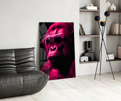 Neon pink and black glass wall art depicting a sunglasses-wearing ape displayed in modern living room with gray sofa and shelving.