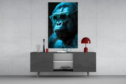 Blue-tinted gorilla wearing sunglasses displayed as framed glass wall art above a dark console table with red lamp and decorative objects.