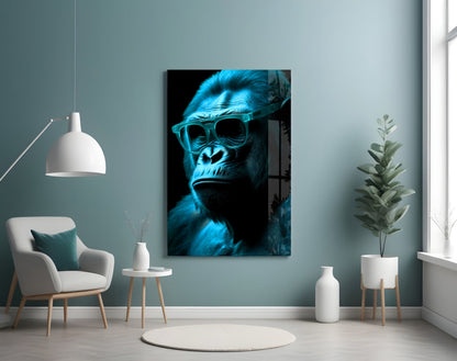 Blue neon-lit gorilla wearing sunglasses displayed on wall above white chair in minimalist interior setting.