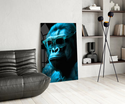 Blue neon gorilla wearing sunglasses displayed as glass wall art in modern living room with gray sofa and shelving.