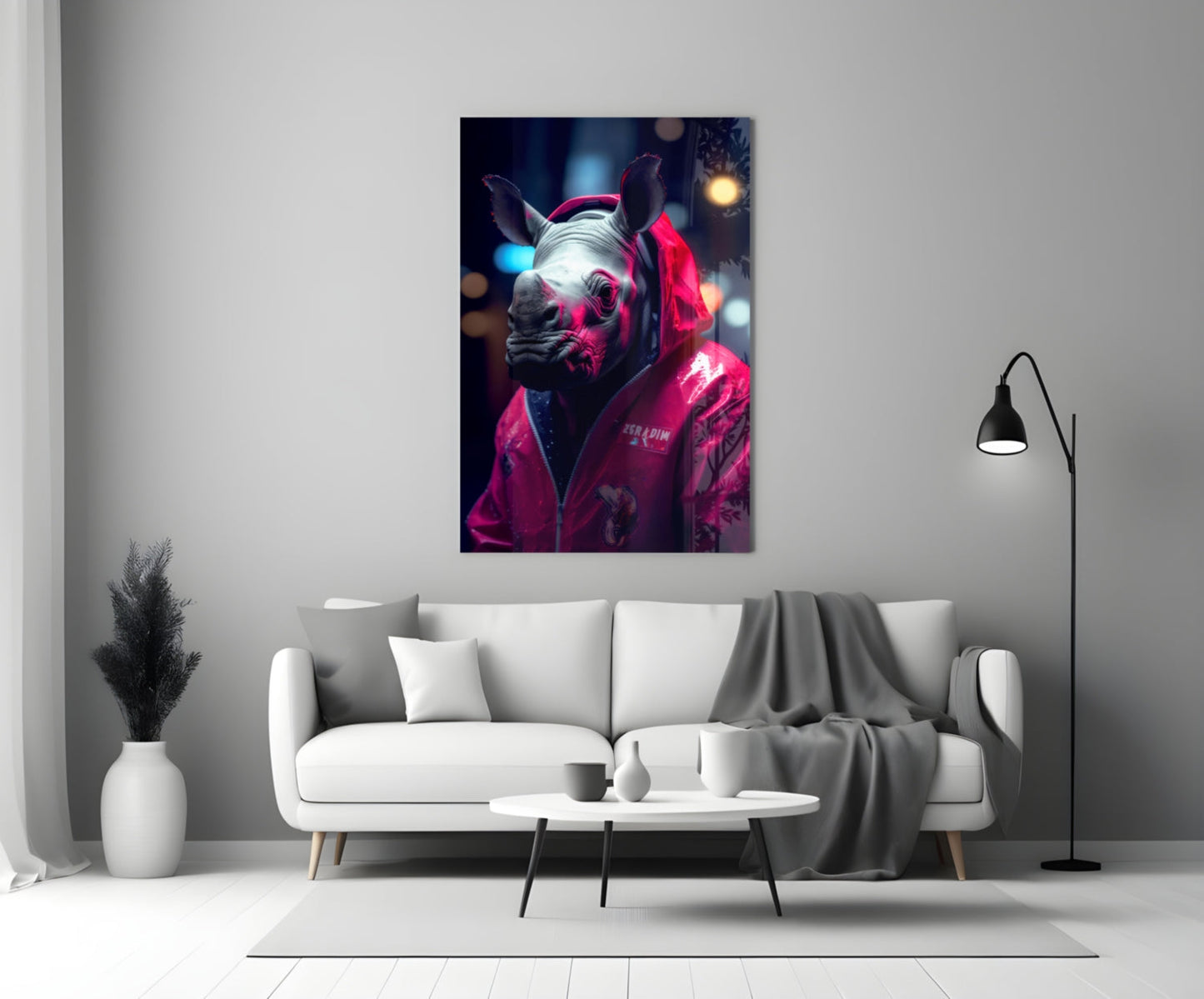 Neon-lit rhino wearing hot pink jacket displayed on white living room wall above gray sofa.
