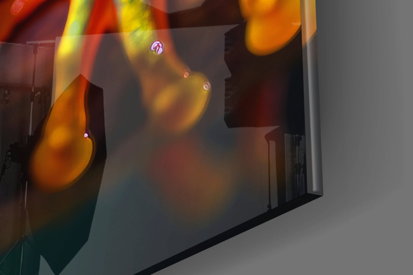 Colorful glass wall art panels with orange, yellow, and red hues displayed against a light gray wall, showing close-up detail of the glass surfaces and light refraction.