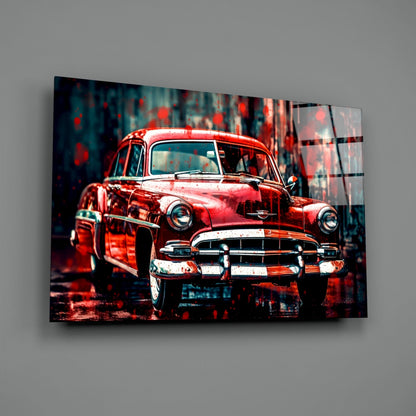 Red vintage 1950s American car with chrome bumper displayed on glass wall art against blurred urban background.