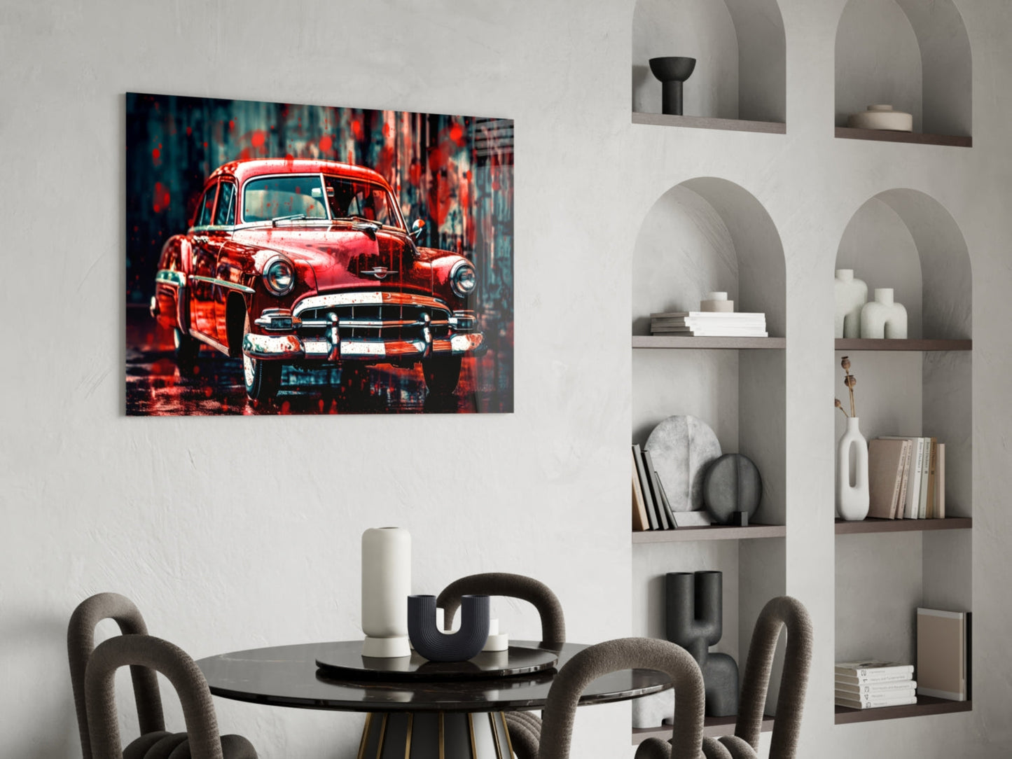 Red vintage American car glass wall art hanging above a round black dining table with gray chairs in a modern interior with white shelving.