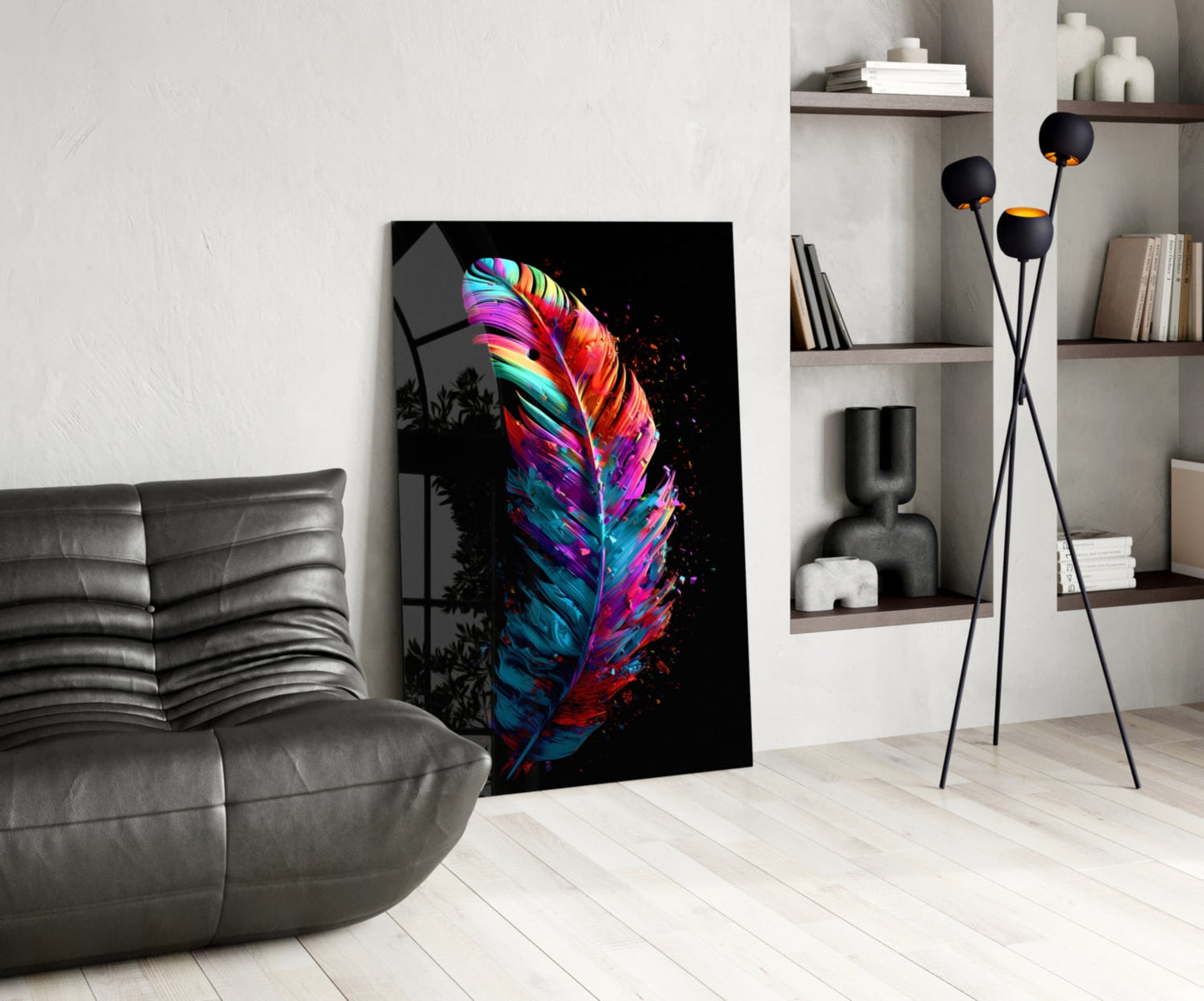 Colorful neon feather glass art displayed on floor against white wall in modern living room with gray sofa and shelving.