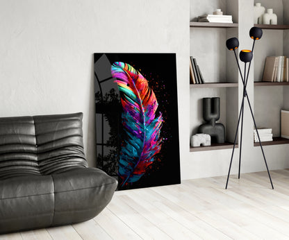 Colorful neon feather glass art displayed on floor against white wall in modern living room with gray sofa and shelving.